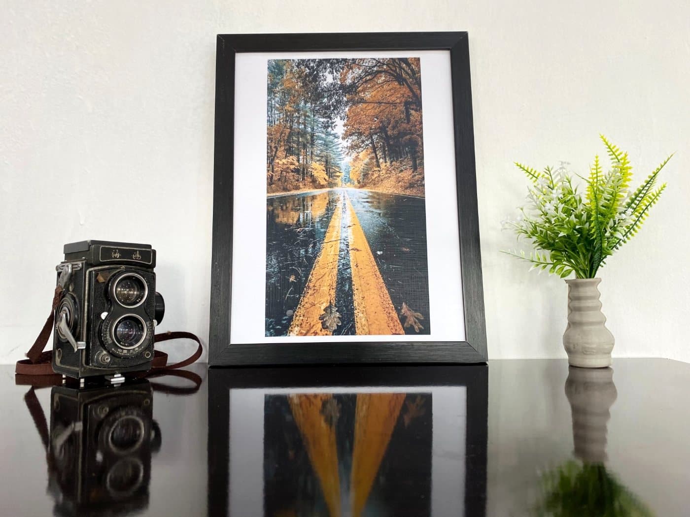 Autumn road print in a 12×16 black frame, styled on a desk